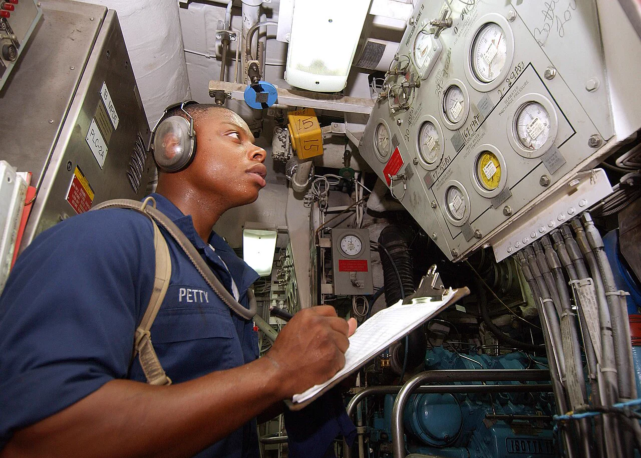 Marine engineer inspecting machinery in a ship engine room